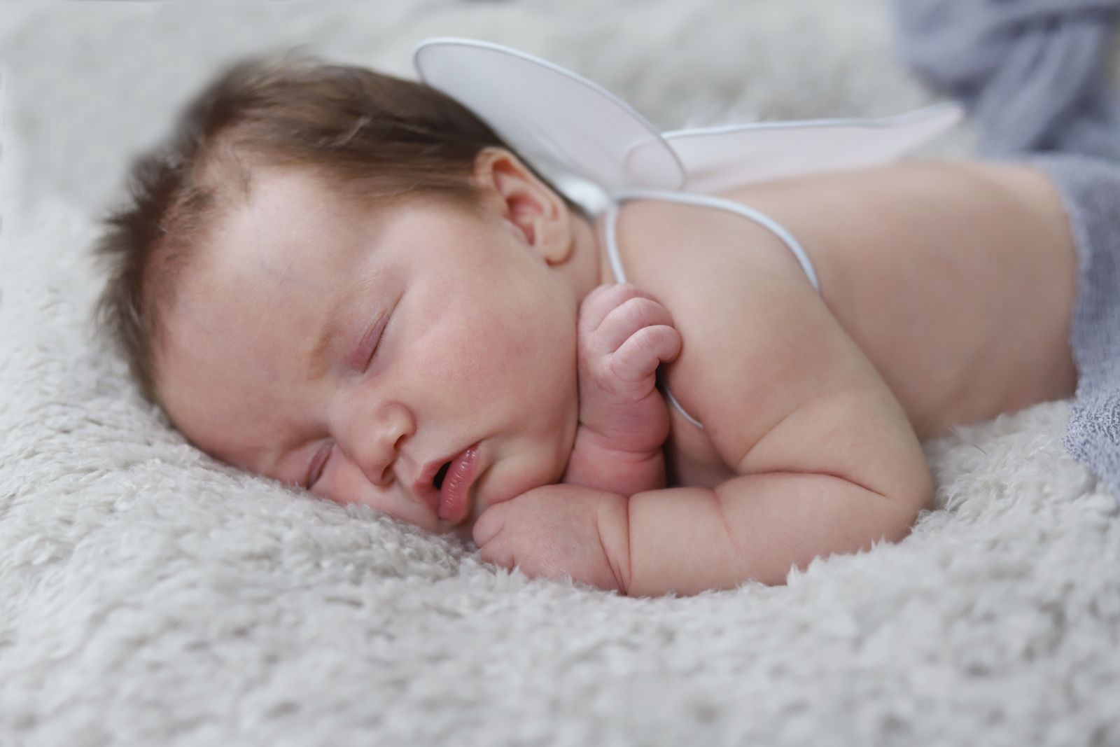 A newborn baby sleeping peacefully in a softly lit bed